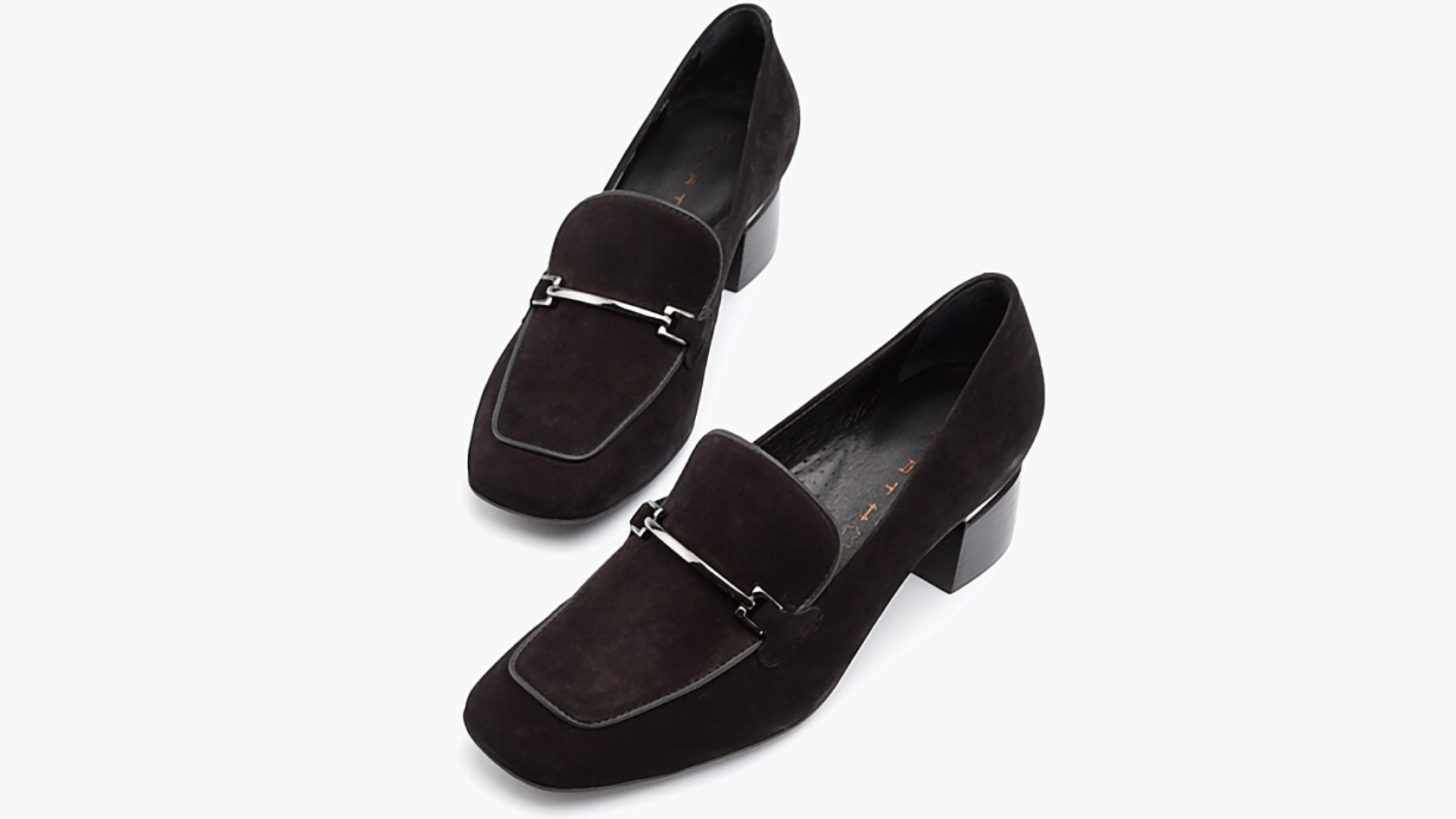 A pair of Wirth mule heels with a black suede upper and metal detailing against a neutral background. 